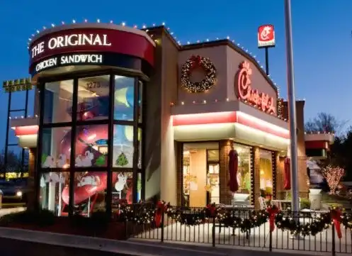 Restaurant storefront decorated with Christmas lights, a wreath, and garland at dusk