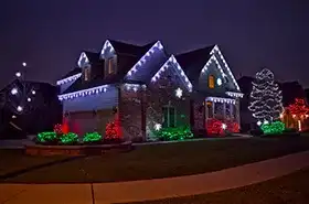 Home with multicolor Christmas lights on the roofline and shrubs