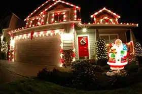 Home with red and white roofline lights and a lit Santa figure