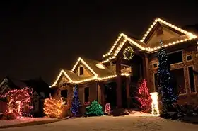 Home with warm white lights on every gable and lit trees